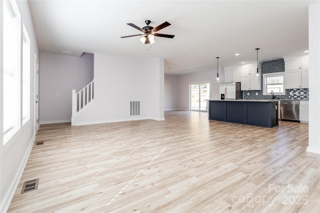 unfurnished living room featuring sink, light hardwood / wood-style flooring, and ceiling fan