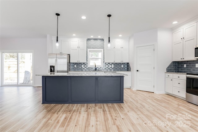 kitchen featuring white cabinetry, stainless steel appliances, a kitchen island, and hanging light fixtures