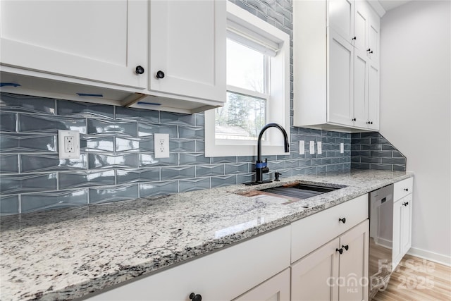 kitchen with sink, white cabinetry, light stone counters, dishwasher, and backsplash