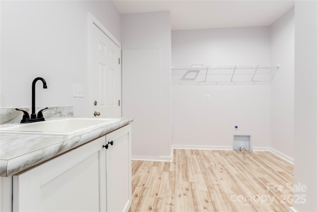 laundry area featuring cabinets, hookup for an electric dryer, sink, and light hardwood / wood-style flooring