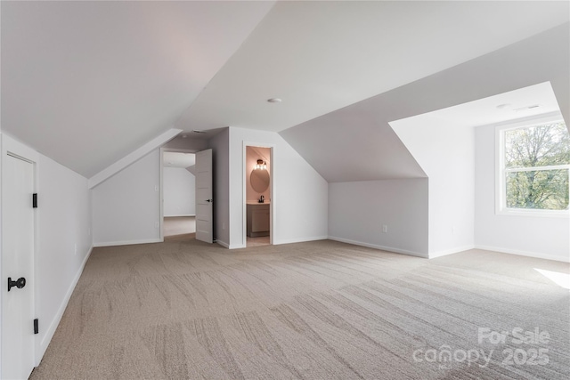 bonus room featuring vaulted ceiling and light colored carpet