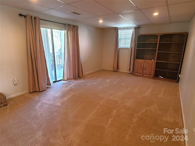 spare room featuring a paneled ceiling and light carpet