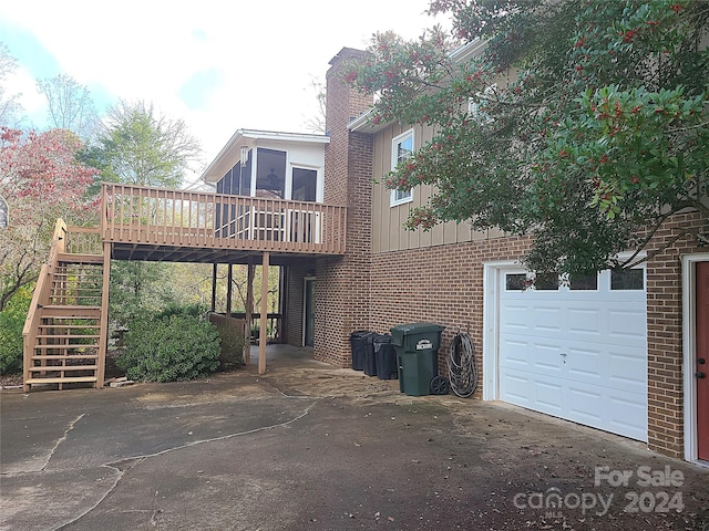 rear view of property with a garage and a wooden deck