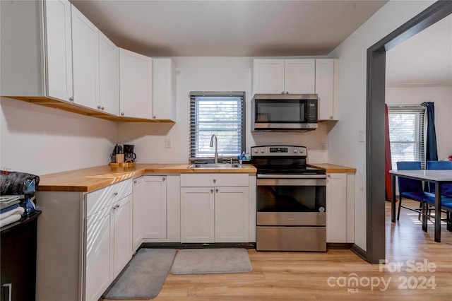 kitchen featuring wooden counters, appliances with stainless steel finishes, light hardwood / wood-style floors, and white cabinetry