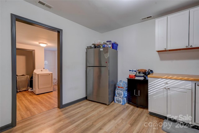 kitchen featuring light hardwood / wood-style flooring, white cabinets, washer / dryer, and stainless steel fridge