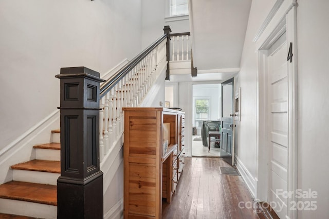 staircase with hardwood / wood-style floors and a high ceiling