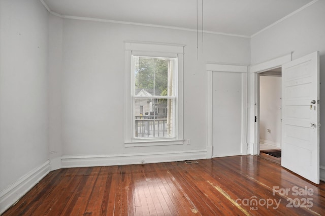 unfurnished room with ornamental molding and dark wood-type flooring