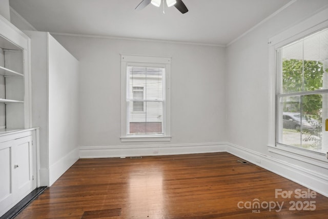 spare room with crown molding, a healthy amount of sunlight, and dark hardwood / wood-style floors