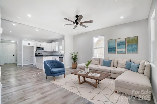 living room featuring sink, ceiling fan, and light hardwood / wood-style flooring