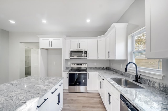 kitchen with light stone countertops, white cabinetry, appliances with stainless steel finishes, and sink