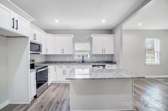 kitchen featuring stainless steel appliances, a center island, sink, and white cabinets