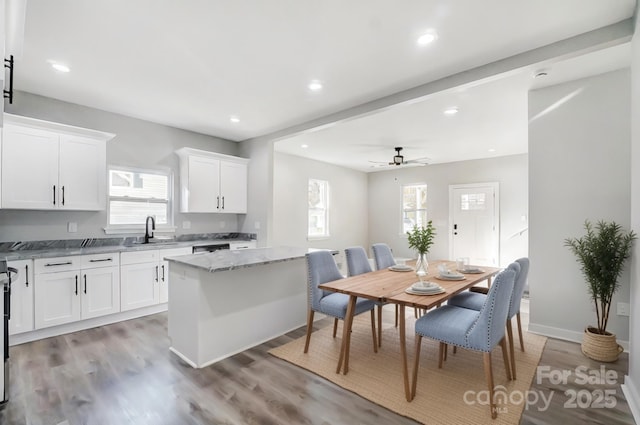 kitchen with light stone counters, a center island, light hardwood / wood-style flooring, ceiling fan, and white cabinets