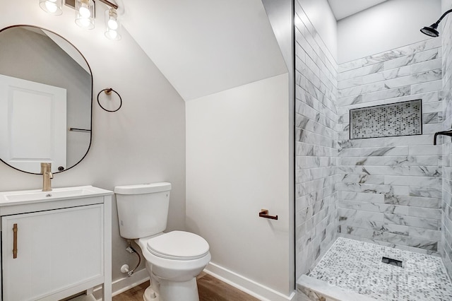 bathroom with wood-type flooring, a tile shower, vanity, and toilet