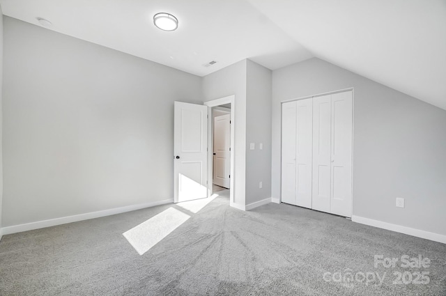 unfurnished bedroom featuring vaulted ceiling, light colored carpet, and a closet