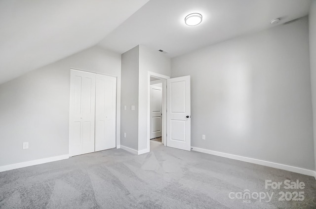 unfurnished bedroom with vaulted ceiling, light colored carpet, and a closet