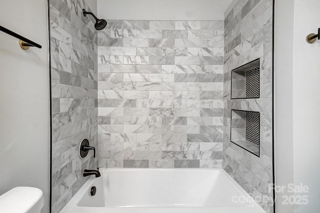 bathroom with toilet and tiled shower / bath combo