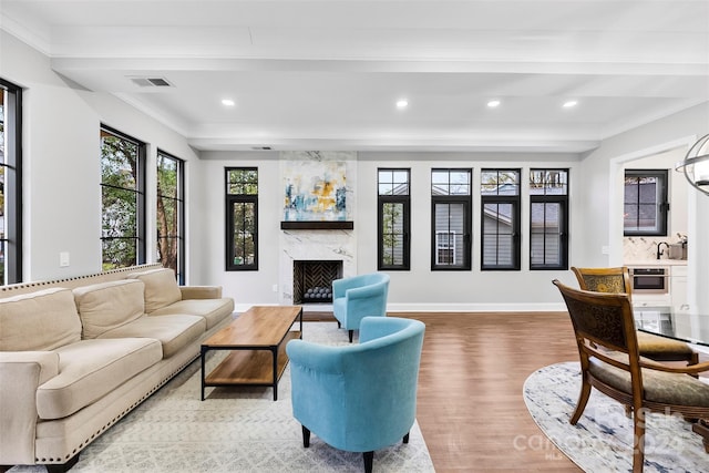 living room featuring a high end fireplace, hardwood / wood-style flooring, and crown molding