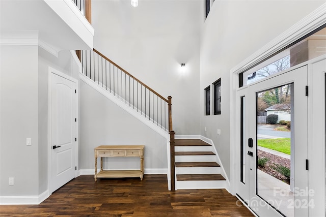 foyer featuring crown molding, dark hardwood / wood-style flooring, and a towering ceiling