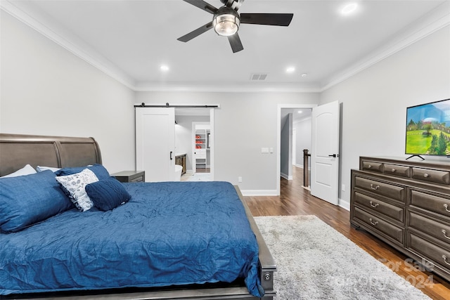 bedroom with ceiling fan, a barn door, dark hardwood / wood-style flooring, and crown molding