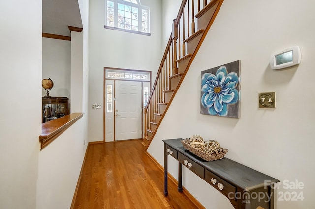 foyer entrance with wood-type flooring and a high ceiling