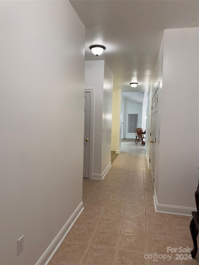 hallway featuring vaulted ceiling and light tile patterned floors