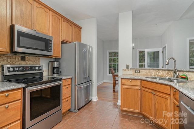 kitchen with light stone counters, decorative backsplash, sink, light tile patterned floors, and appliances with stainless steel finishes