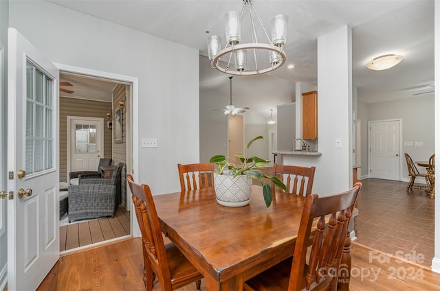 dining room with ceiling fan with notable chandelier and light hardwood / wood-style flooring