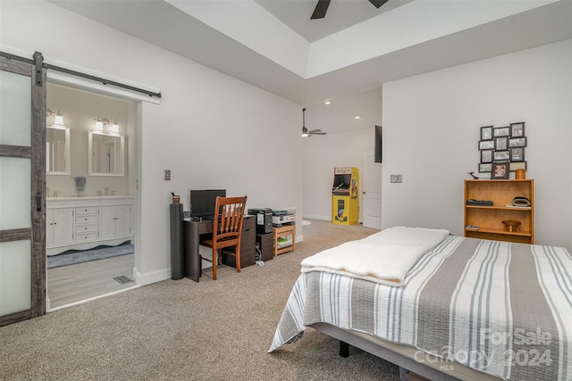 carpeted bedroom featuring connected bathroom, a barn door, and ceiling fan