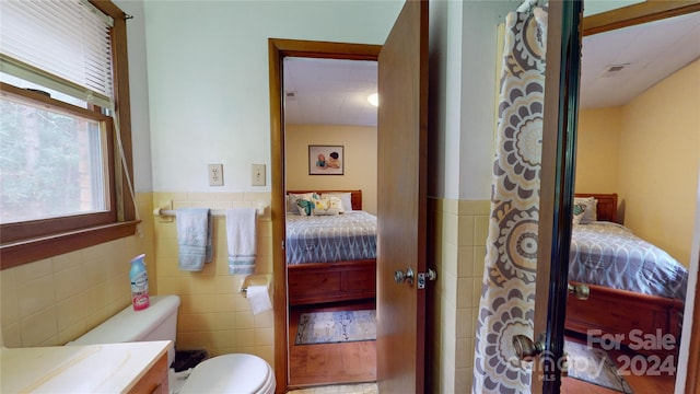 bathroom with vanity, tile walls, and toilet