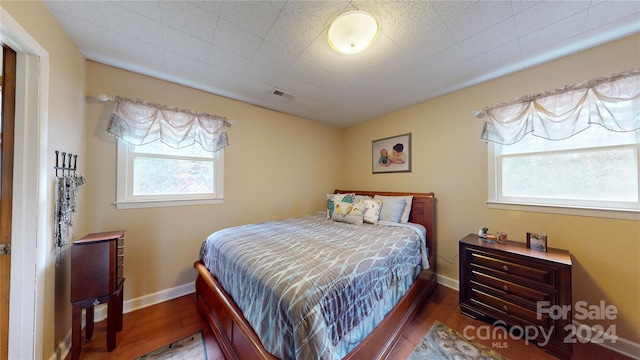 bedroom featuring multiple windows and dark hardwood / wood-style floors