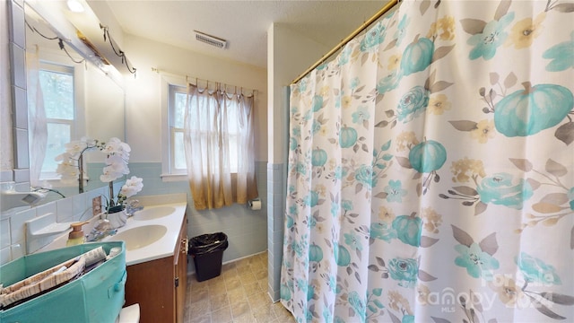 bathroom with vanity, a healthy amount of sunlight, tile walls, and walk in shower