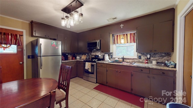 kitchen featuring decorative backsplash, appliances with stainless steel finishes, sink, light tile patterned floors, and decorative light fixtures