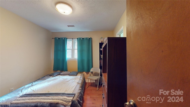 bedroom featuring a textured ceiling and hardwood / wood-style flooring