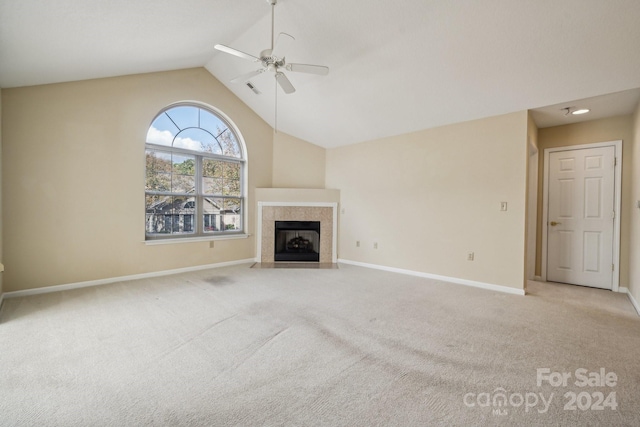 unfurnished living room featuring ceiling fan, a tile fireplace, vaulted ceiling, and light colored carpet