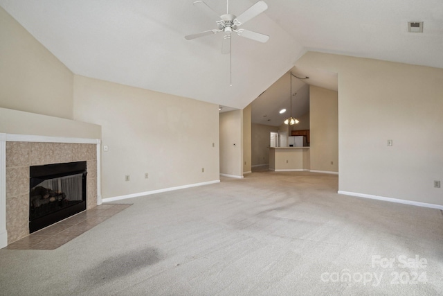 unfurnished living room with ceiling fan with notable chandelier, light colored carpet, a tile fireplace, and vaulted ceiling