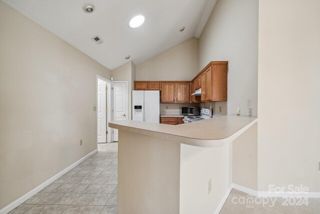 kitchen featuring high vaulted ceiling, kitchen peninsula, light tile patterned flooring, and stainless steel appliances