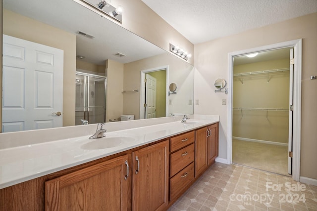 bathroom with toilet, an enclosed shower, vanity, and a textured ceiling