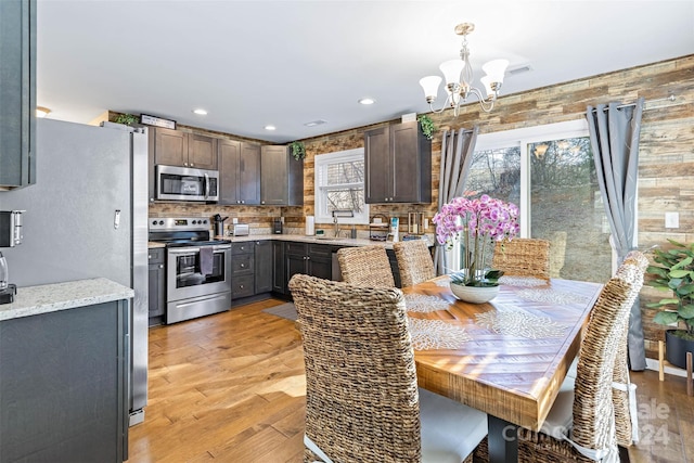 dining space featuring light wood-type flooring, sink, and an inviting chandelier