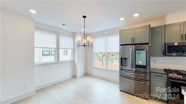 kitchen with stainless steel appliances, an inviting chandelier, backsplash, hanging light fixtures, and gray cabinets