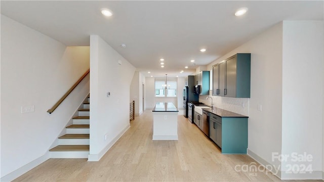 kitchen with tasteful backsplash, a kitchen island, light wood-type flooring, appliances with stainless steel finishes, and a chandelier