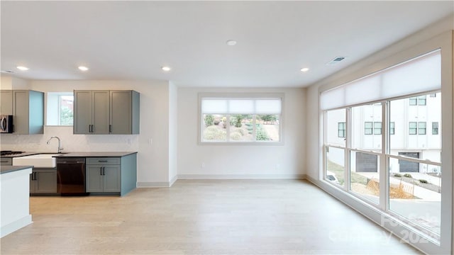 kitchen featuring light hardwood / wood-style floors, decorative backsplash, black dishwasher, and a healthy amount of sunlight