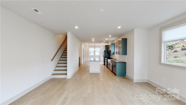 interior space with light hardwood / wood-style floors, tasteful backsplash, and stainless steel fridge