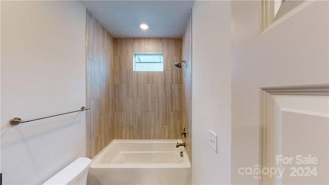 bathroom featuring toilet and tiled shower / bath