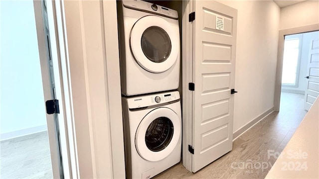 laundry area featuring stacked washer and dryer and light wood-type flooring