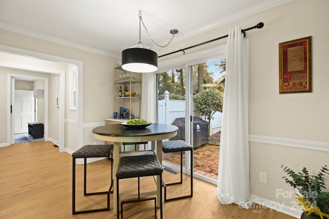 dining room with wood-type flooring and crown molding