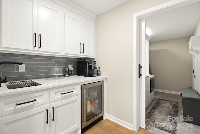 bar with light stone countertops, tasteful backsplash, beverage cooler, light hardwood / wood-style flooring, and white cabinetry