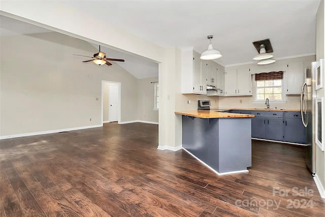 kitchen featuring pendant lighting, a kitchen bar, butcher block countertops, and dark wood-type flooring