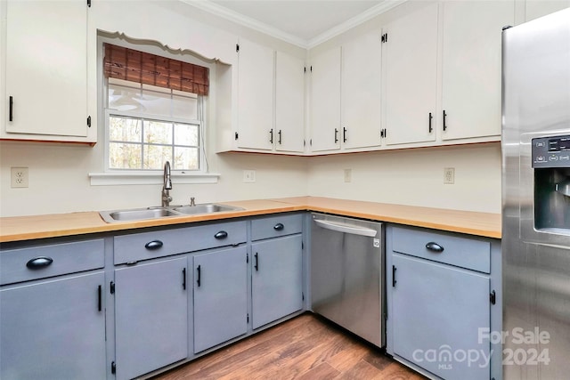 kitchen with stainless steel appliances, dark wood-type flooring, butcher block counters, sink, and crown molding