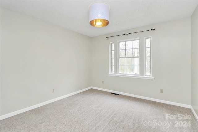 carpeted empty room with a textured ceiling