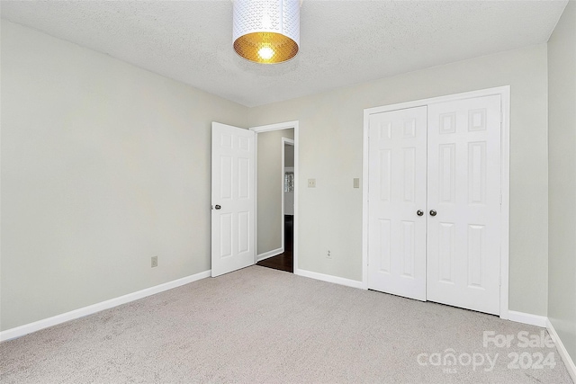 unfurnished bedroom with a closet, a textured ceiling, and carpet flooring